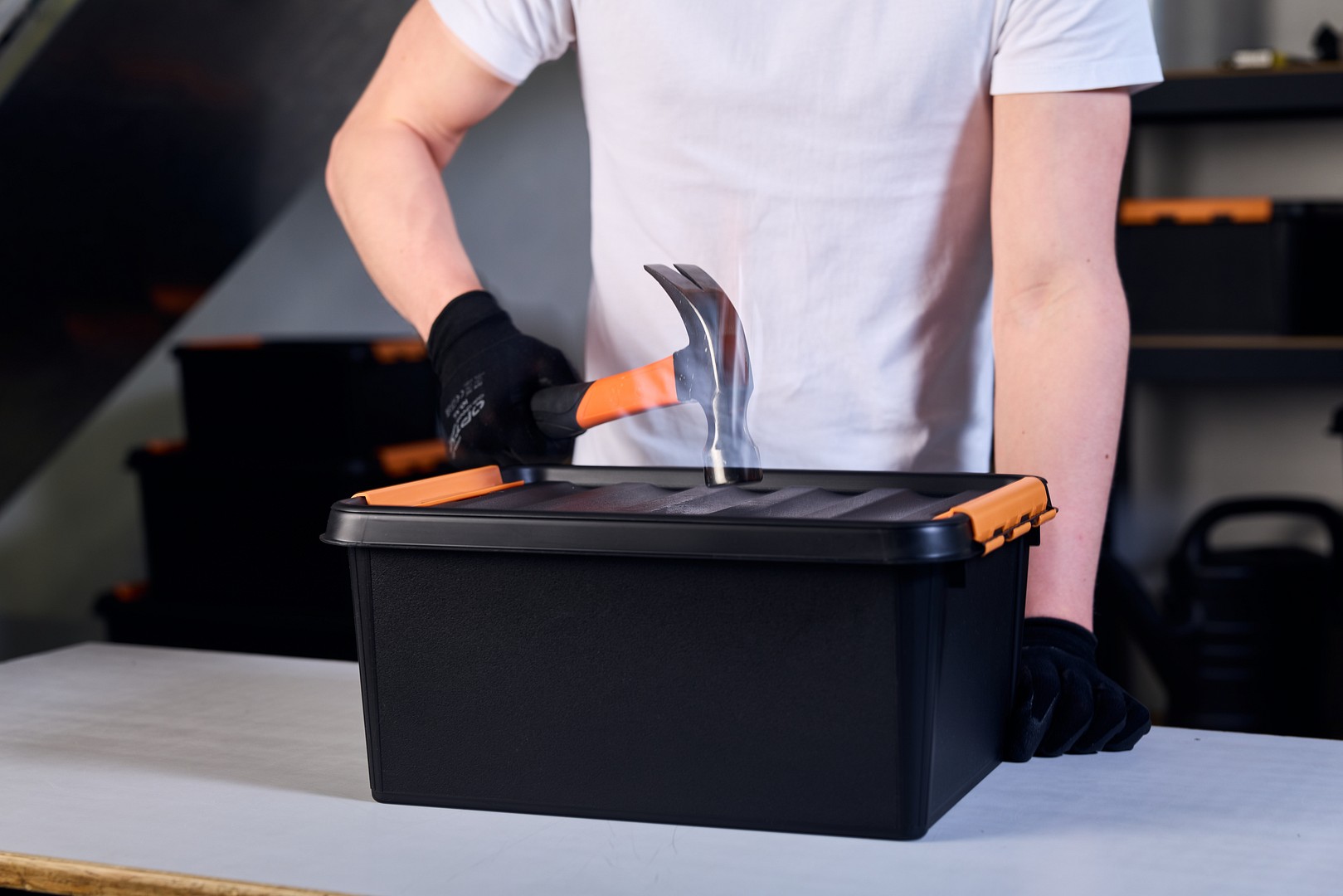 Une main avec un marteau frappant une boîte de rangement SmartStore™ Pro